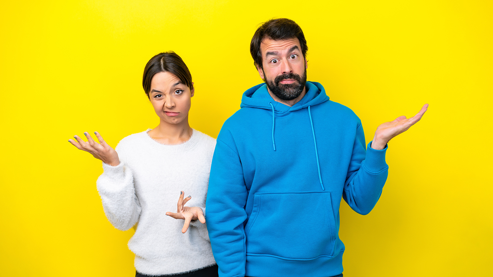 Young caucasian couple isolated on yellow background having doubts and with confuse face expression