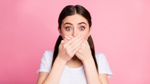 Close-up portrait of her she nice attractive lovely scared brunet girl closing mouth with palms oops reaction isolated over pink pastel color background