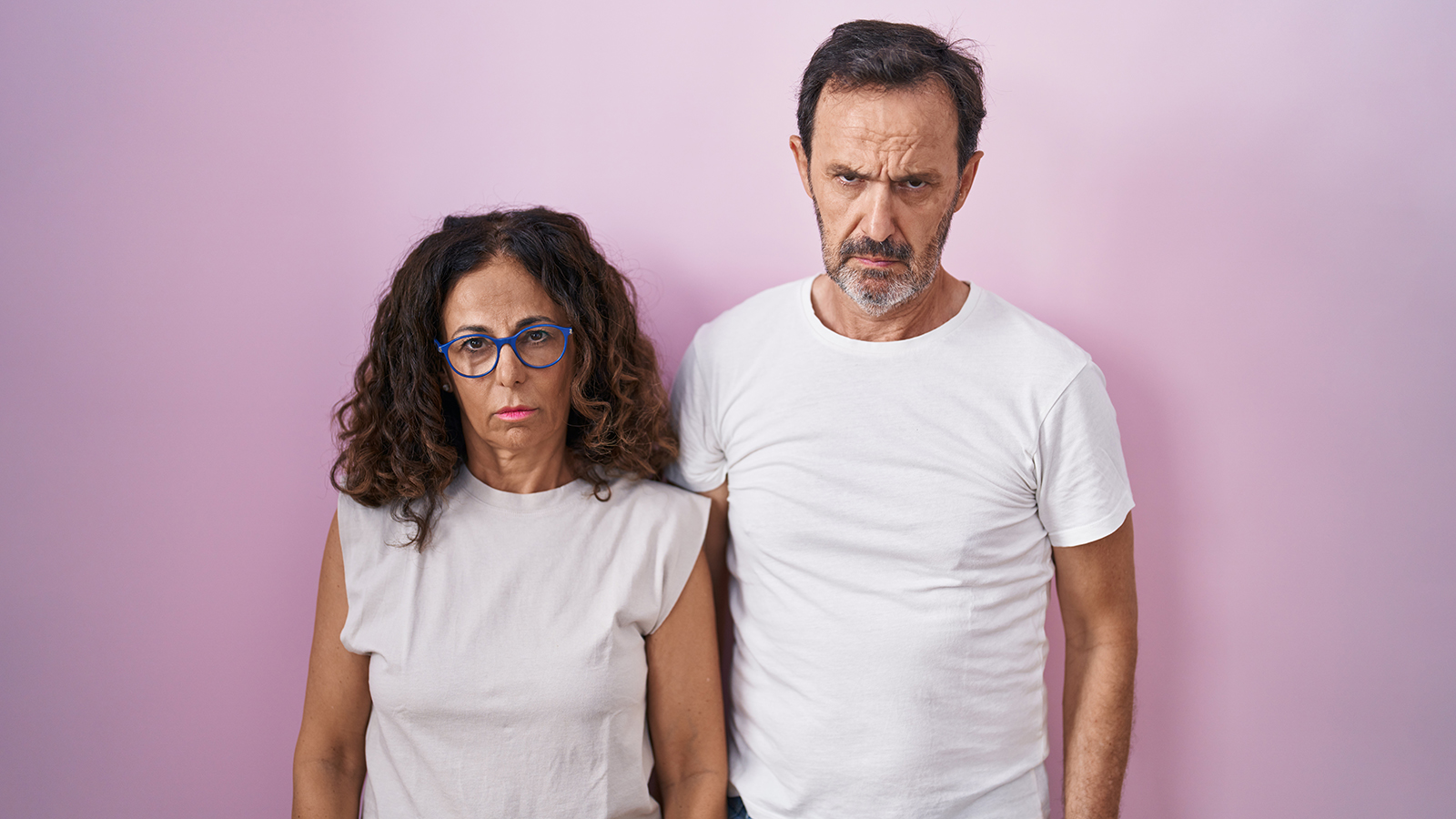 Middle age hispanic couple together over pink background skeptic and nervous, frowning upset because of problem. negative person.
