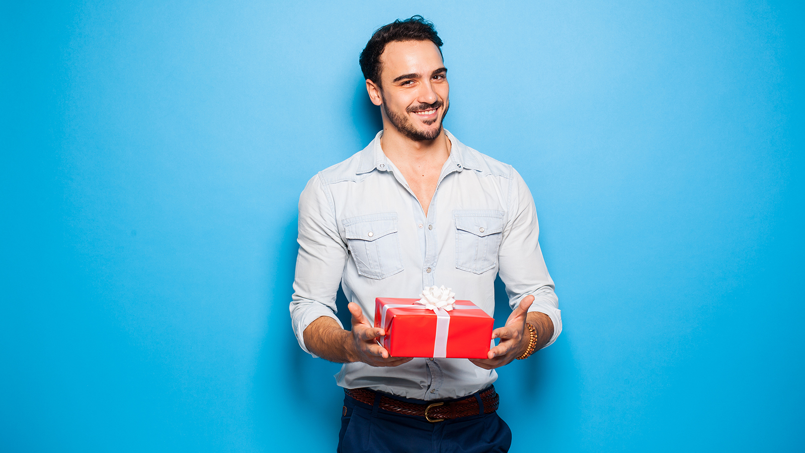 smiling sexy man on blue background with christmas gift