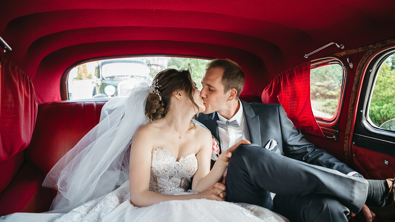 Happy bride and groom are kissing in the car