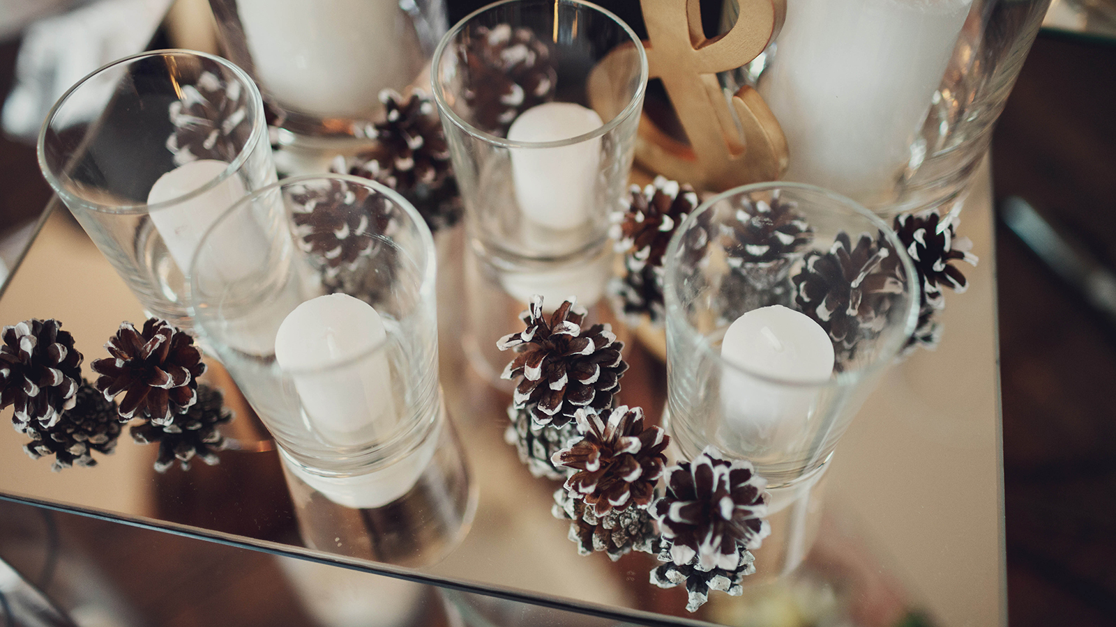 white candles in a transparent glasses and cones lies on table
