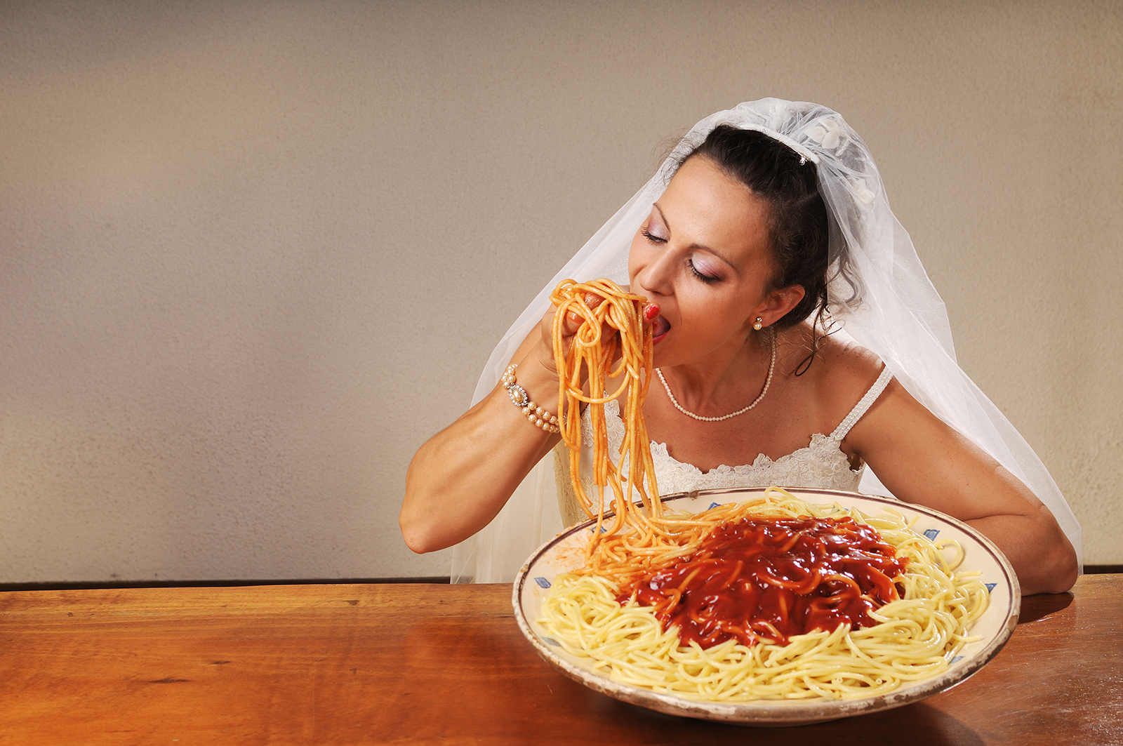 young bride eats spaghetti with tomato in rustic setting