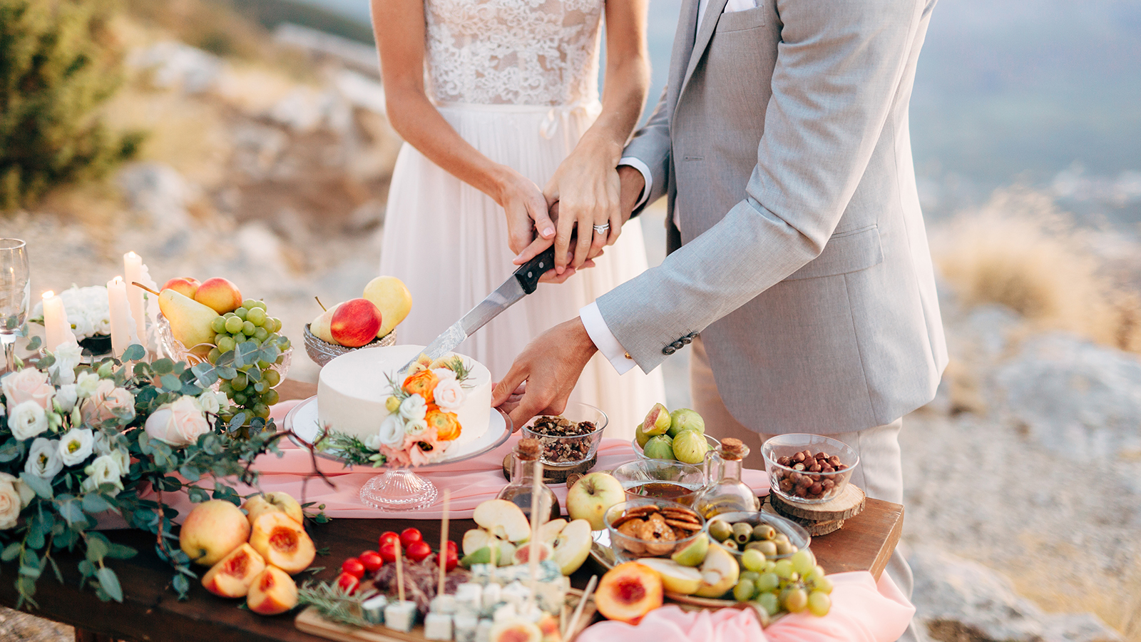 The bride and groom are cutting a cake during a buffet table after the wedding ceremony on Mount Lovcen, close-up