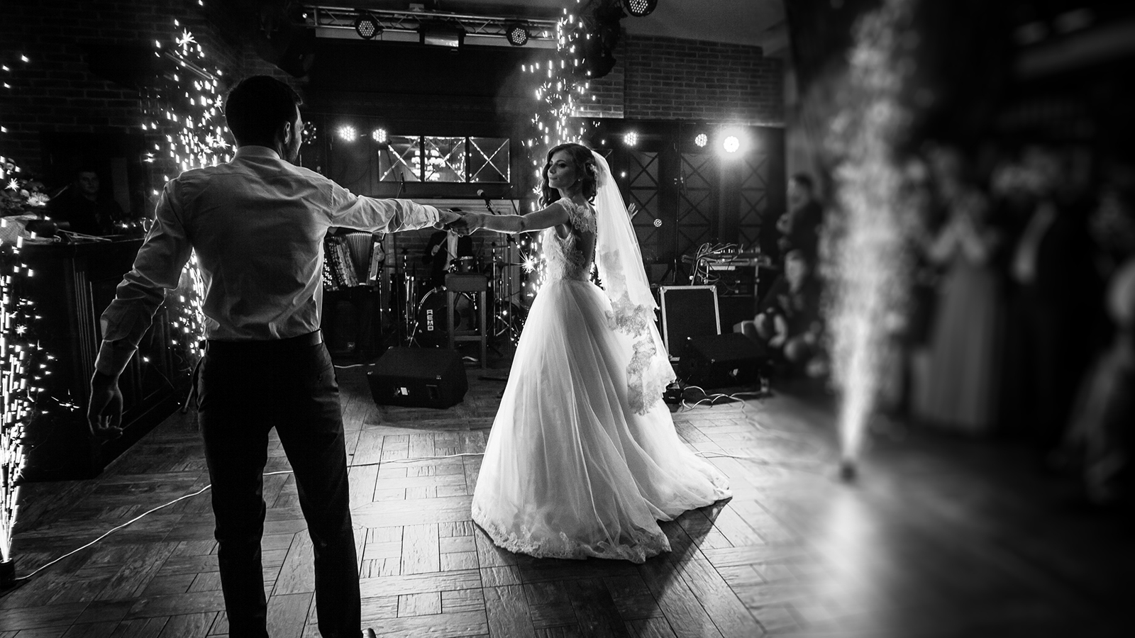 Beautiful newlywed couple first dance at wedding reception surrounded by smoke and lights and sparks b&w